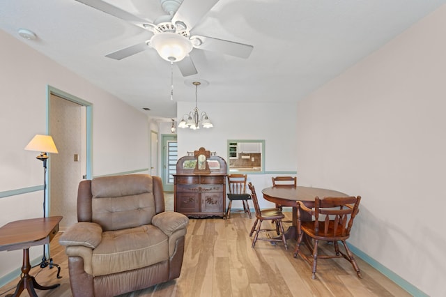 dining area with ceiling fan with notable chandelier and light hardwood / wood-style flooring