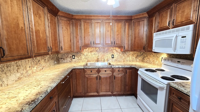 kitchen featuring sink, light stone counters, a textured ceiling, white appliances, and light tile patterned flooring