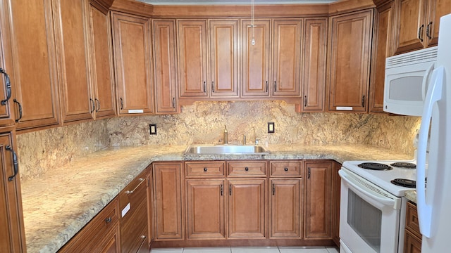 kitchen with white appliances, a sink, light stone countertops, and brown cabinets