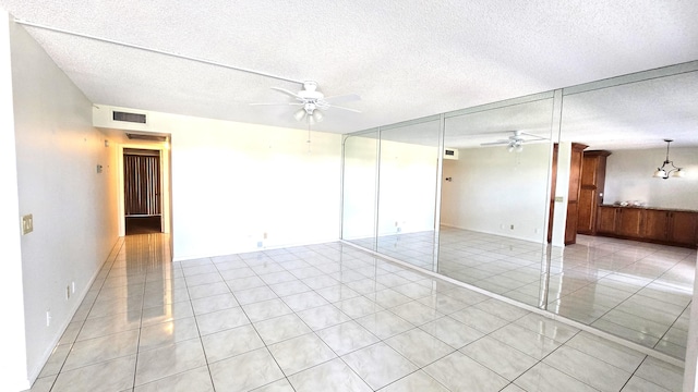 tiled empty room featuring a textured ceiling and ceiling fan