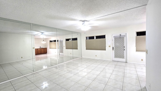 tiled spare room with ceiling fan and a textured ceiling