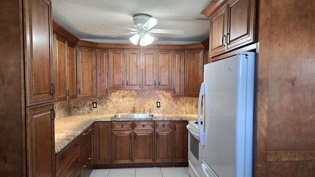 kitchen featuring light stone counters, white appliances, ceiling fan, sink, and light tile patterned floors