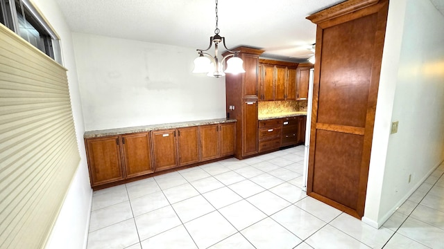 kitchen featuring decorative backsplash, light stone countertops, hanging light fixtures, and an inviting chandelier