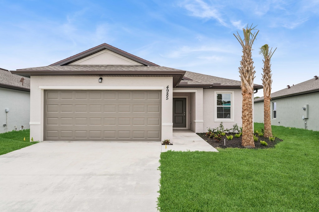 ranch-style house with roof with shingles, stucco siding, a front yard, a garage, and driveway