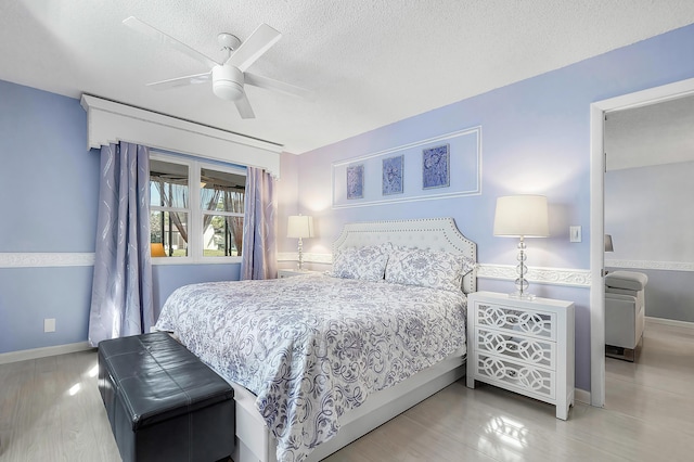 bedroom featuring ceiling fan, light hardwood / wood-style floors, and a textured ceiling