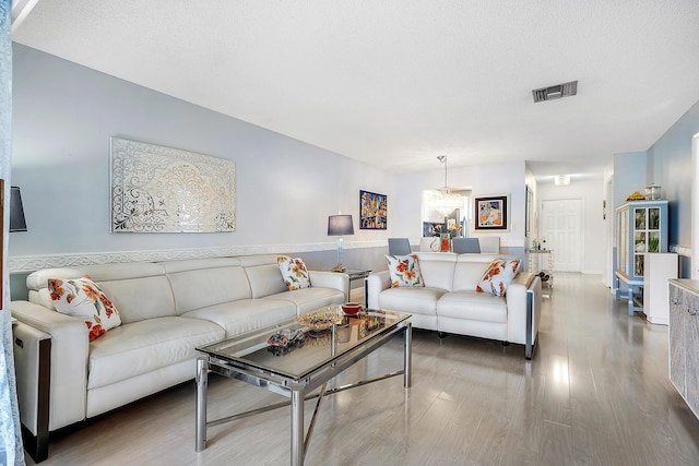 living room with a chandelier, wood-type flooring, and a textured ceiling