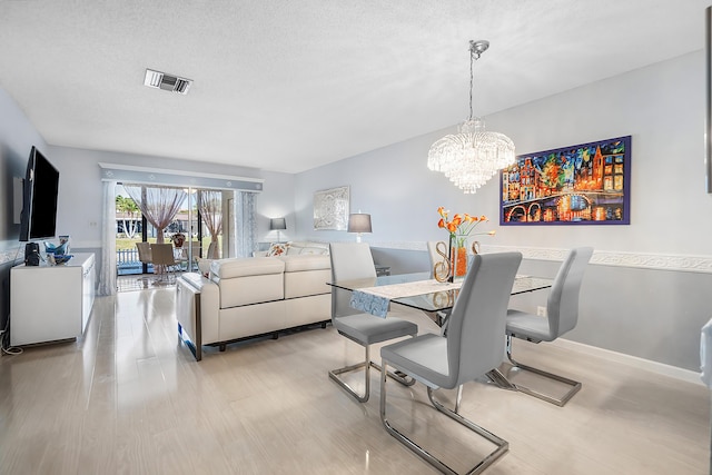 dining room featuring an inviting chandelier, a textured ceiling, and light wood-type flooring