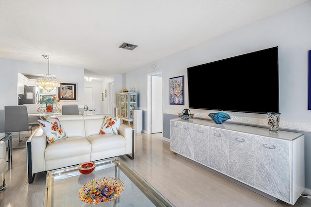 living room featuring a notable chandelier and light wood-type flooring