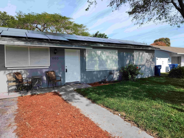 view of front of home with a front yard and solar panels