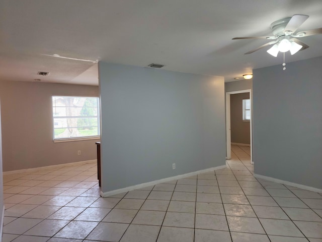 empty room with ceiling fan and light tile patterned floors