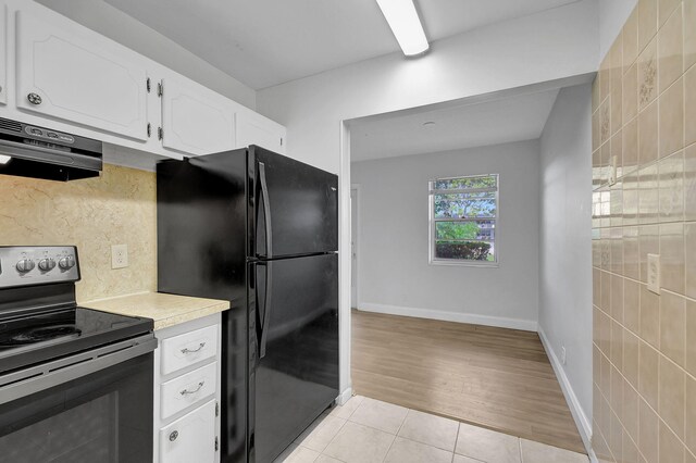 kitchen featuring black refrigerator, extractor fan, light hardwood / wood-style flooring, white cabinetry, and stainless steel electric range