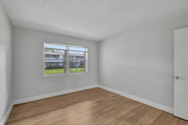 empty room featuring a textured ceiling and light hardwood / wood-style floors