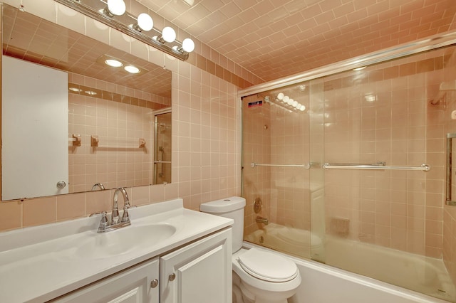 full bathroom featuring vanity, toilet, shower / bath combination with glass door, and tile walls