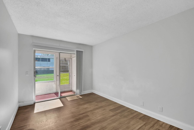 unfurnished room featuring dark hardwood / wood-style flooring and a textured ceiling