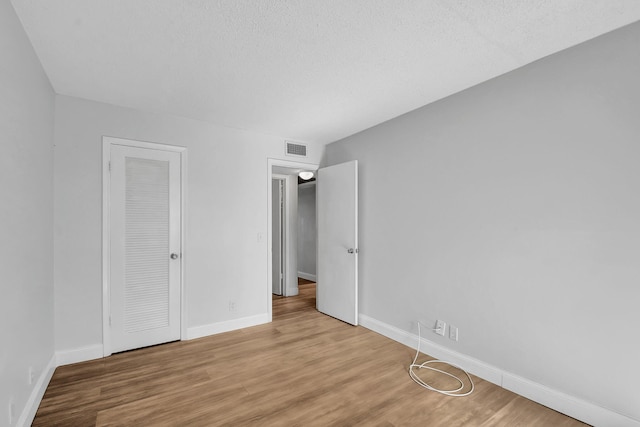 unfurnished bedroom with a closet, a textured ceiling, and light wood-type flooring