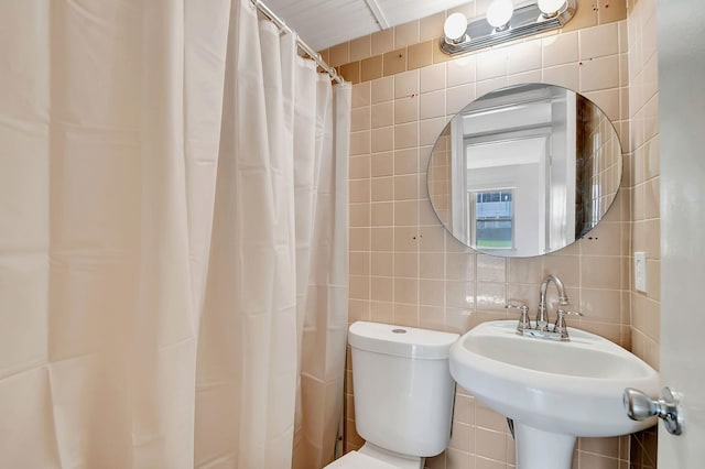 bathroom featuring backsplash, sink, toilet, and tile walls