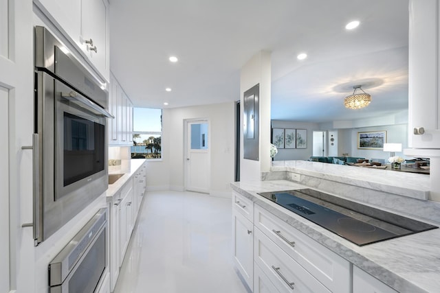 kitchen featuring white cabinets, light stone countertops, stainless steel appliances, and an inviting chandelier