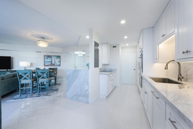 kitchen featuring white cabinets, decorative backsplash, light stone countertops, and sink