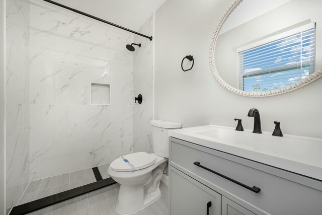 bathroom featuring a tile shower, tile patterned flooring, vanity, and toilet