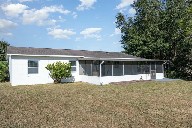 back of property with a lawn and a sunroom