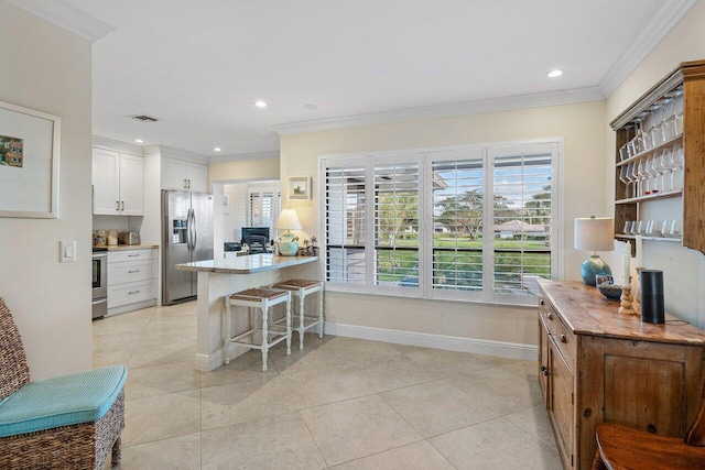 kitchen with a breakfast bar, white cabinets, crown molding, kitchen peninsula, and stainless steel appliances