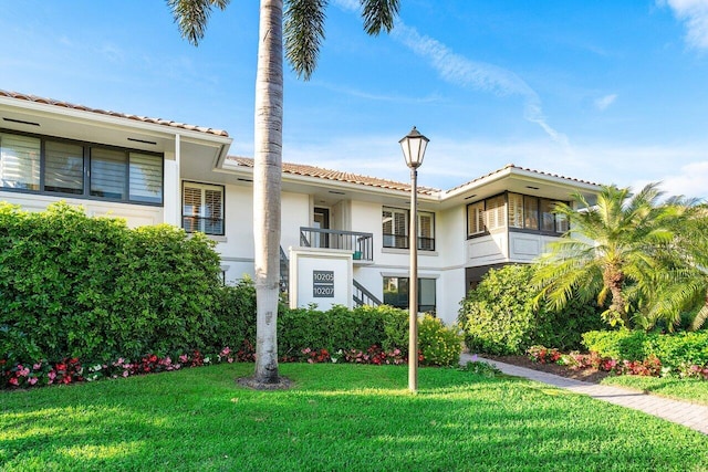 view of front of home with a balcony and a front lawn