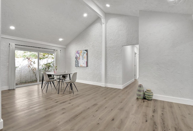 dining area with high vaulted ceiling, hardwood / wood-style flooring, and beam ceiling