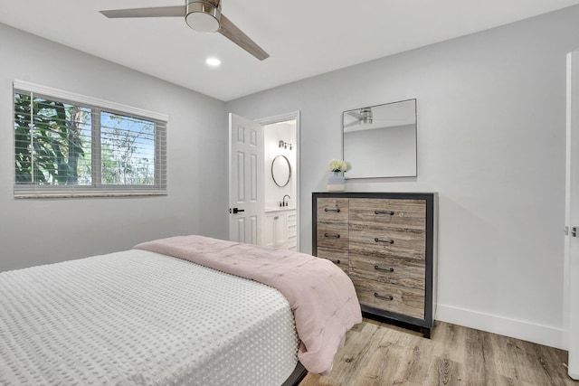 bedroom featuring ceiling fan, light wood-type flooring, ensuite bathroom, and sink