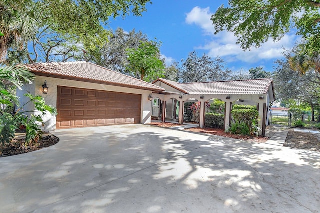 mediterranean / spanish-style home featuring driveway, a tile roof, an attached garage, a gate, and stucco siding