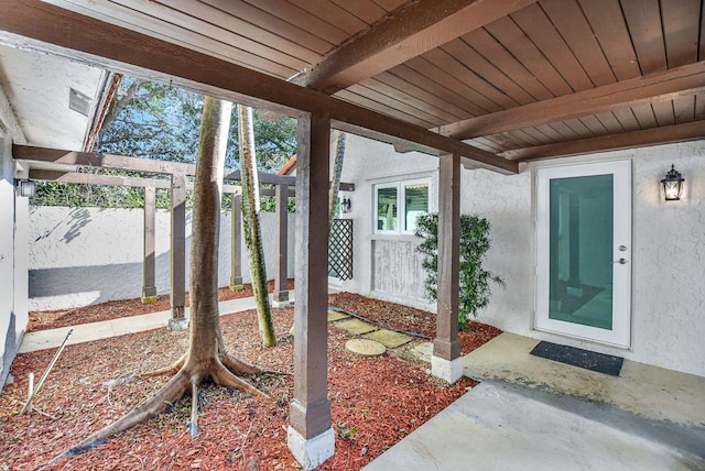 view of exterior entry with fence and stucco siding