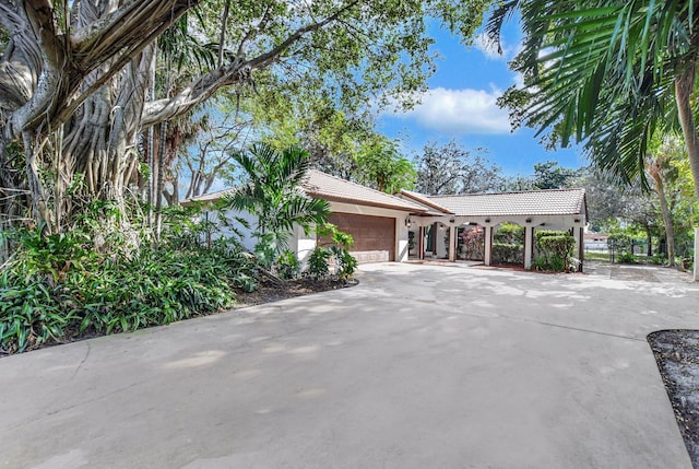 view of side of home featuring an attached garage, a tiled roof, concrete driveway, and stucco siding