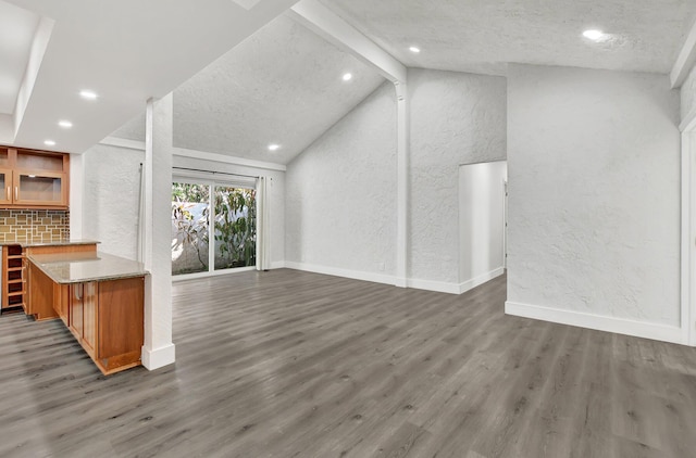 unfurnished living room with a textured ceiling, vaulted ceiling with beams, and dark hardwood / wood-style floors