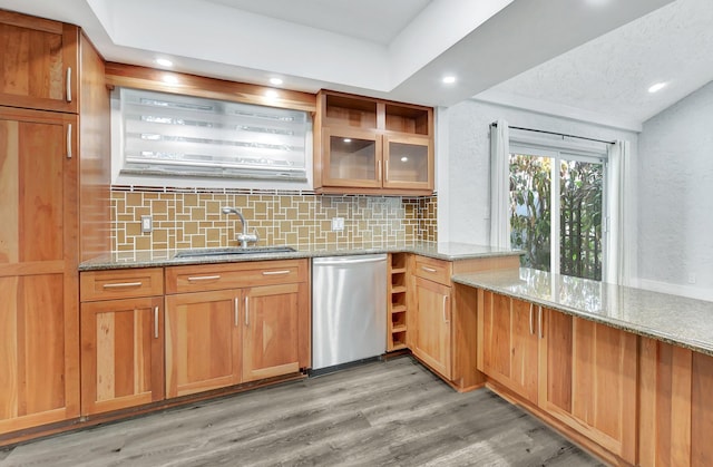 kitchen with sink, light hardwood / wood-style floors, stainless steel dishwasher, backsplash, and light stone countertops