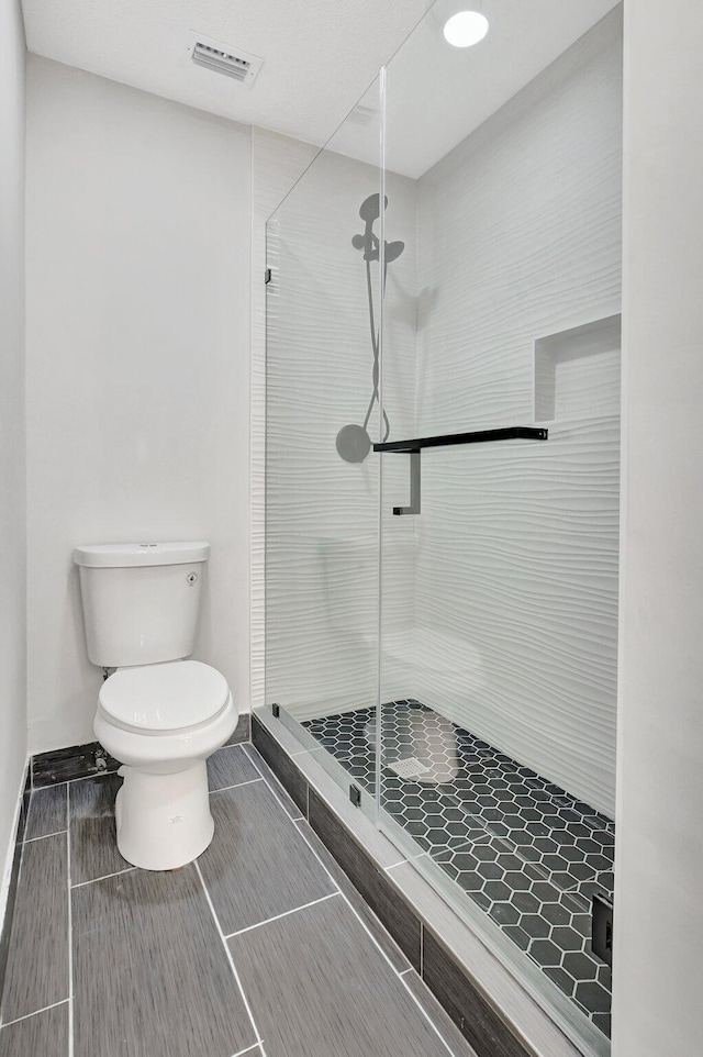 bathroom with toilet and a shower with door