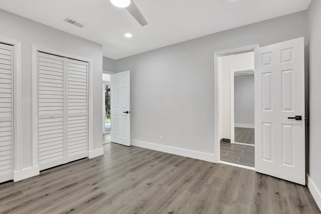 unfurnished bedroom with ceiling fan, wood finished floors, visible vents, and baseboards