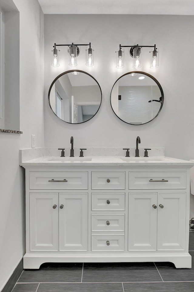 full bathroom with a sink, baseboards, and double vanity