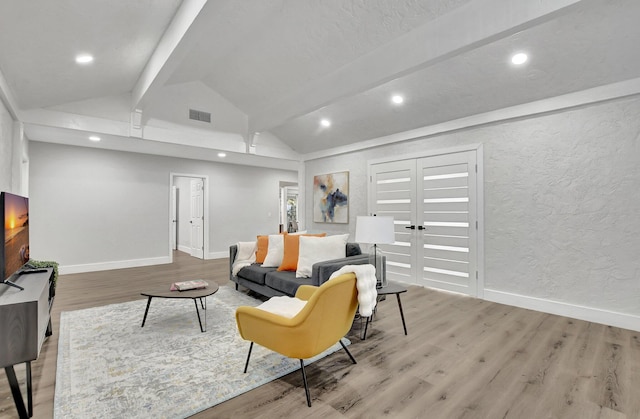 living room featuring lofted ceiling with beams and light hardwood / wood-style floors