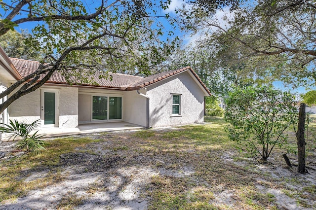 rear view of property featuring a patio area, a tile roof, and stucco siding