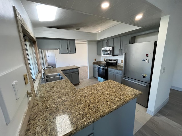 kitchen with stainless steel appliances, a tray ceiling, sink, a center island, and gray cabinets