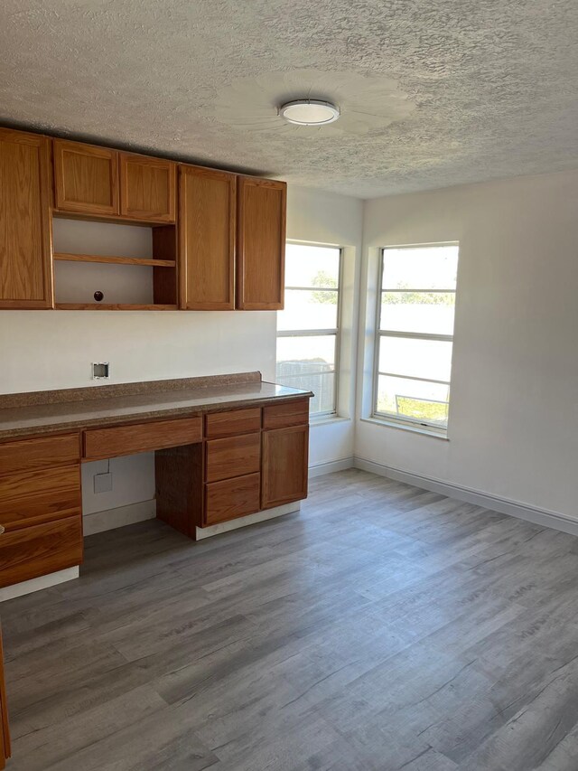 unfurnished office featuring dark hardwood / wood-style floors, built in desk, and a textured ceiling