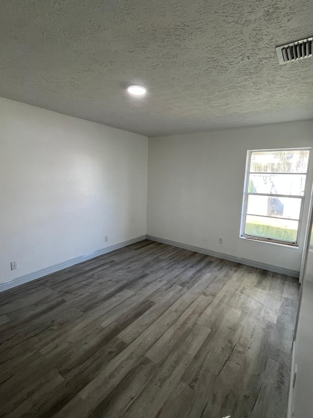 unfurnished room with a textured ceiling and dark hardwood / wood-style floors