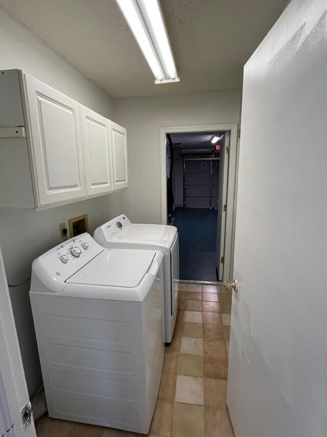 clothes washing area with washer and clothes dryer, light tile patterned floors, and cabinets