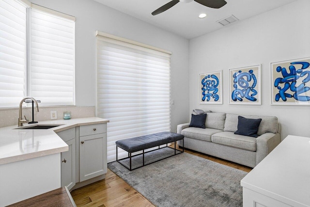 living room featuring light hardwood / wood-style floors, ceiling fan, and sink