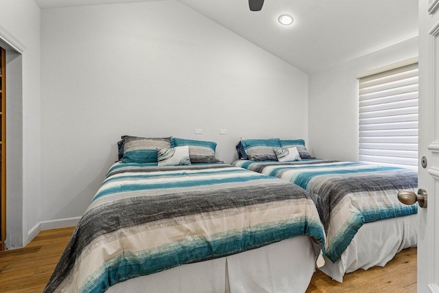 bedroom with ceiling fan, vaulted ceiling, and light wood-type flooring