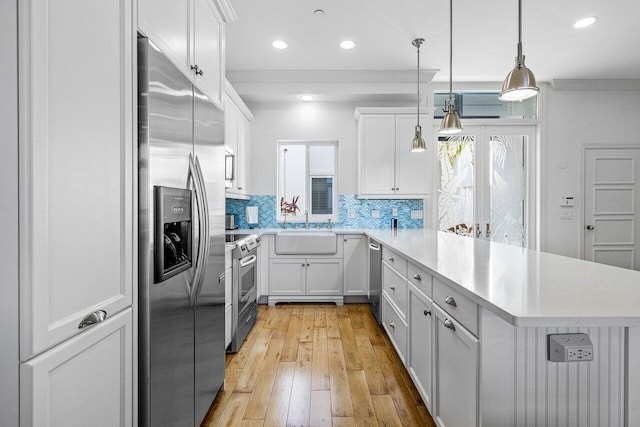 kitchen with white cabinets, appliances with stainless steel finishes, and a wealth of natural light