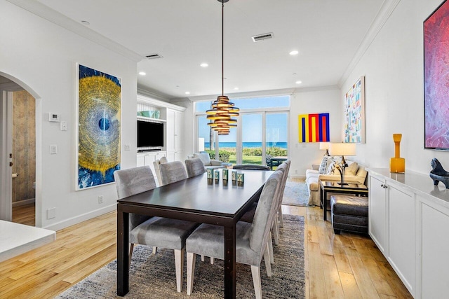 dining room with light hardwood / wood-style floors, a notable chandelier, and ornamental molding