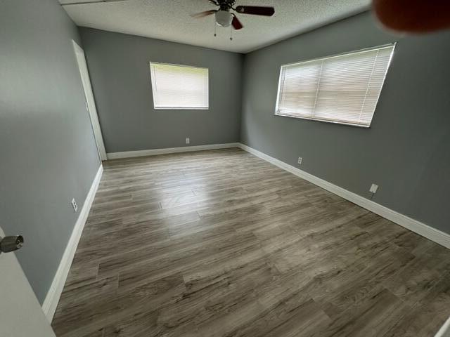 empty room with ceiling fan, wood-type flooring, and a textured ceiling