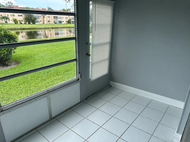 doorway to outside featuring a water view and light tile patterned floors