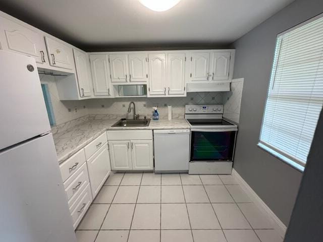 kitchen featuring white appliances, white cabinets, sink, tasteful backsplash, and light tile patterned flooring