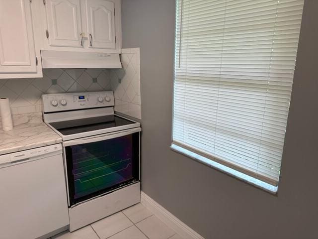 kitchen with backsplash, white appliances, extractor fan, white cabinetry, and light tile patterned flooring